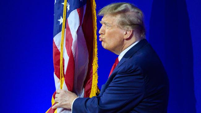 Donald Trump kisses the US flag as he arrives to speak during the annual Conservative Political Action Conference meeting. Picture: AFP.