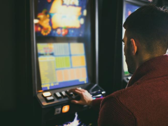 Young man sitting in a casino and gambling on a slot machine.