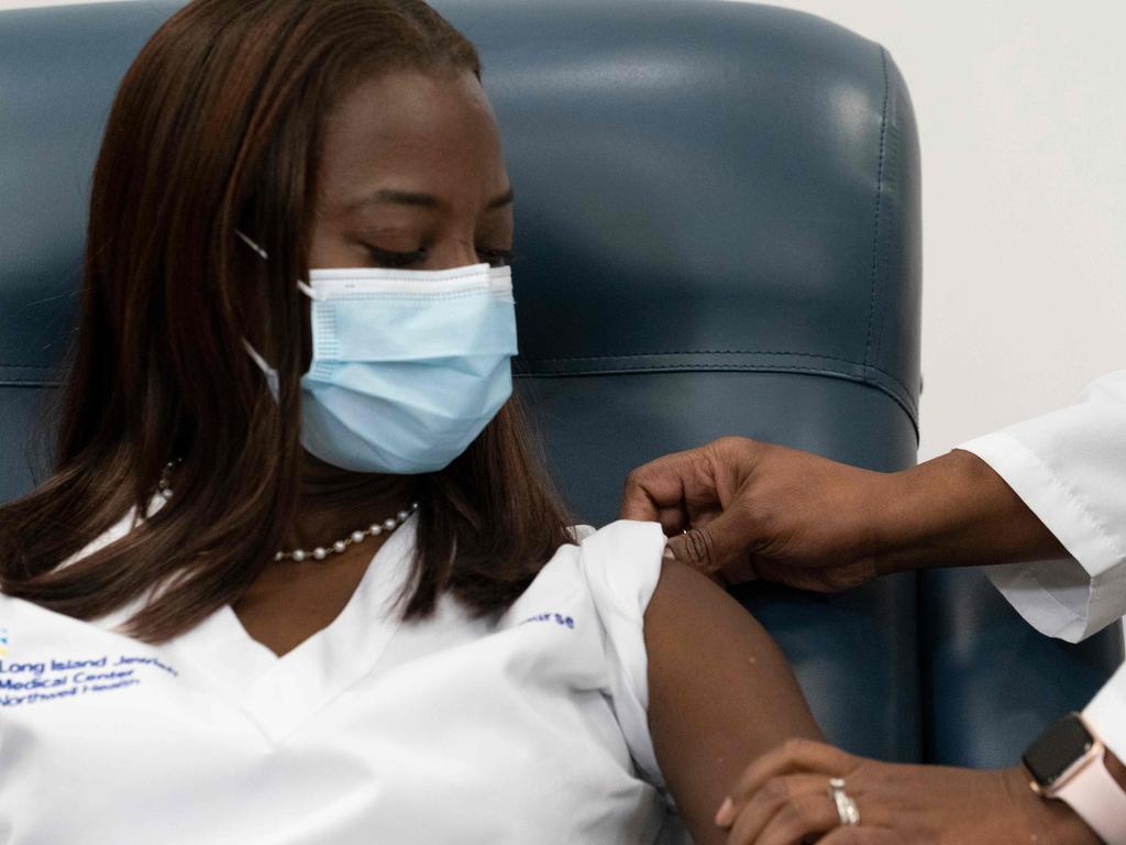 Dr. Michelle Chester (right), rolls up the sleeve of Sandra Lindsay, a nurse at Long Island Jewish Medical Center in New York and the first person to receive the Pfizer-BioNTech COVID-19 vaccine. Picture: Mark Lennihan/AFP