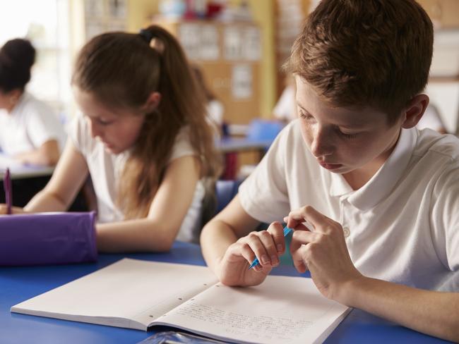 Two kids working at their desks in primary school, close up