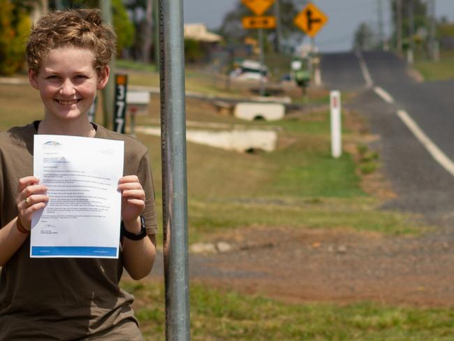 Summer Farrelly stands in front of the three new signs and roadside chevrons that were added to the intersection following the safety audit.