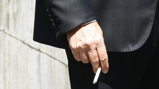 A man carries a lit cigarette in Sydney’s Martin Place, a designated Smoke Free Zone. The City of Sydney is calling on the NSW Government to help them to roll out smoke free areas after admitting it cannot enforce smoking bans. Picture: John Appleyard