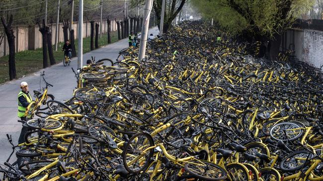 A Chinese mechanic from bike share company Ofo Inc. selects a bike to fix from a pile of thousands of damaged bicycles that were pulled off the streets of Beijing.