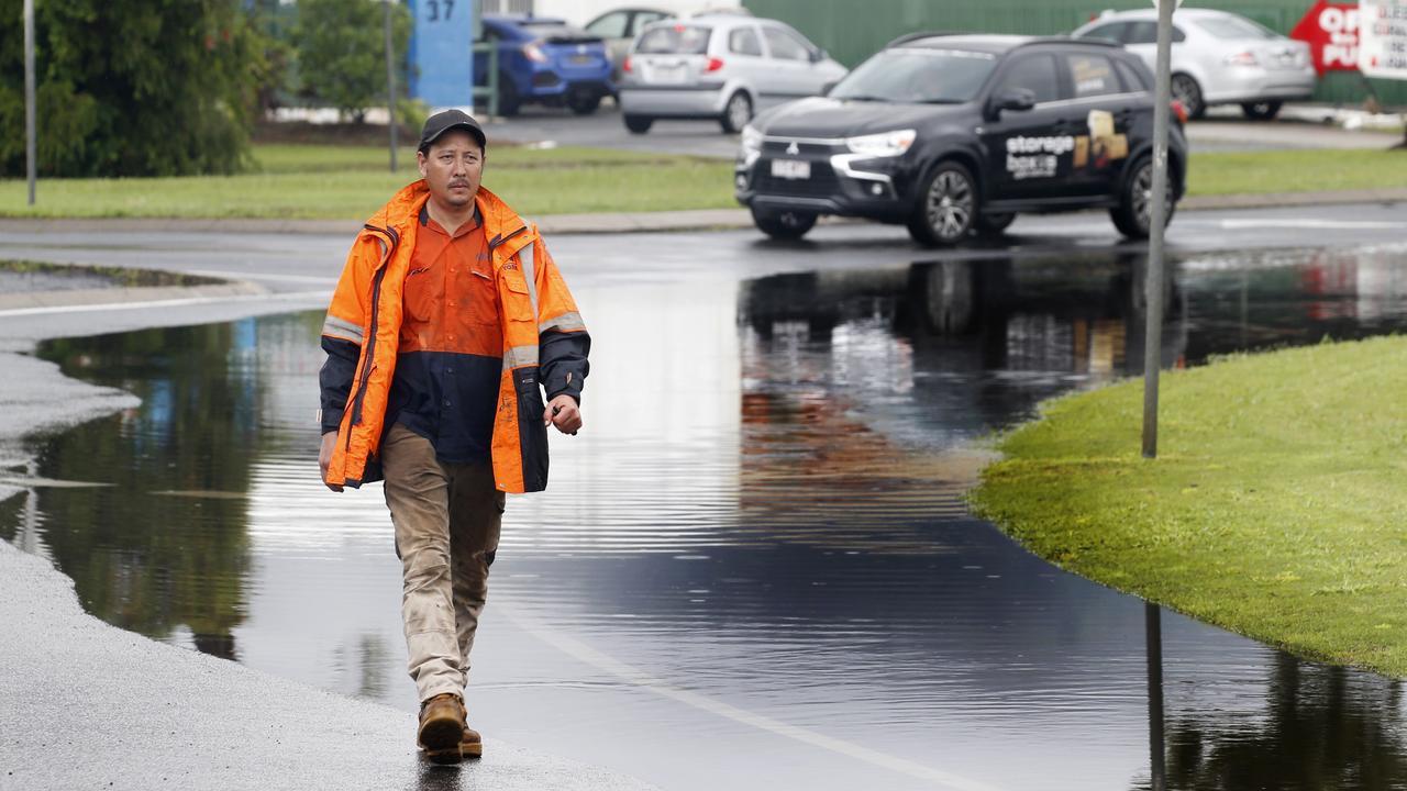 Paul Lim from Century Cranes walks past the floodwater on Aumuller St PICTURE: ANNA ROGERS