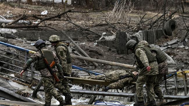 Ukrainian servicemen carry the body of a comrade on a stretcher in the city of Irpin, northwest of Kyiv. Picture: AFP