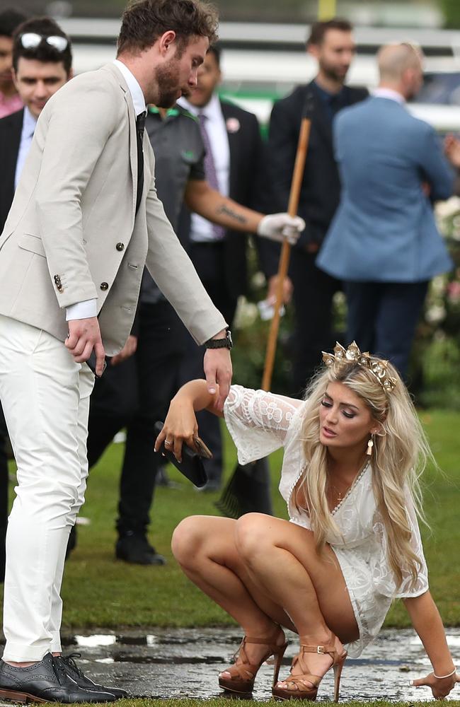 A reveller graciously recovers after slipping in the wet as she makes her way home from Flemington Racecourse. Elsewhere in Australia the scenes were more wild. Picture: Scott Barbour/Getty Images