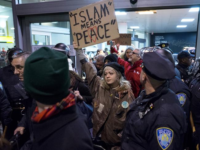 Protesters are surrounded by police officers and travellers as they pass through an exit of Terminal 4 at John F. Kennedy International Airport in New York. Picture: AP