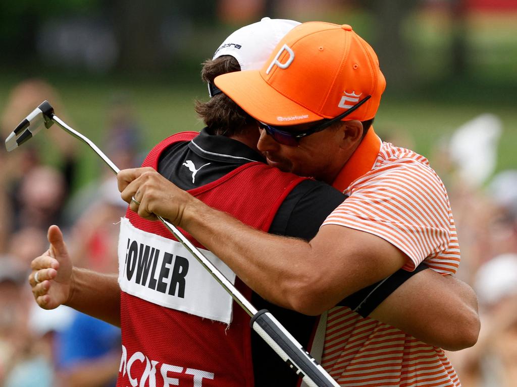 Rickie Fowler of the United States and his caddie, Ricky Romano, celebrate on the 18th green.