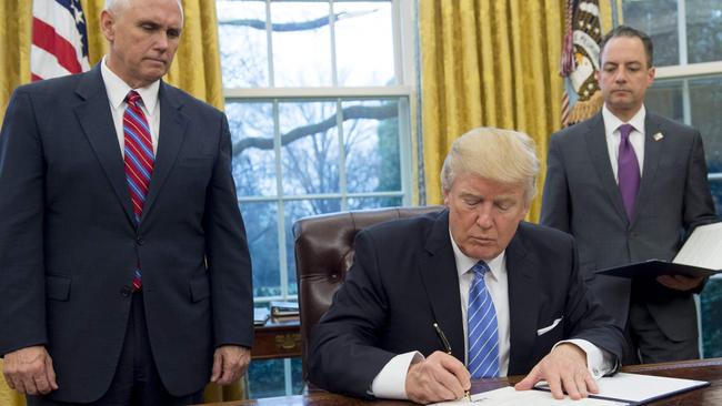 US President Donald Trump signs an executive order withdrawing the US from the Trans-Pacific Partnership, flanked by Vice-President Mike Pence, left, and White House chief of staff Reince Priebus.