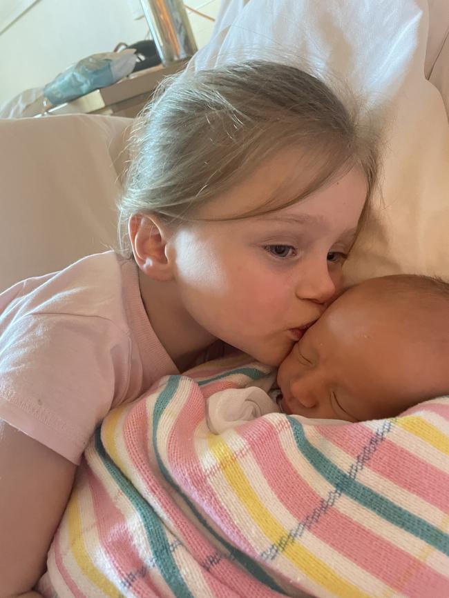 Seven weather presenter Amelia Mulcahy’s daughter Grace giving new baby Ted a kiss.