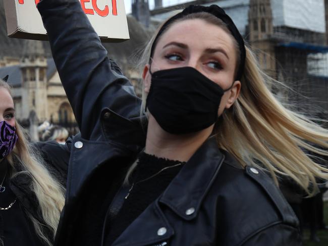 LONDON, ENGLAND - MARCH 15: Members of the public hold up signs during a protest in Parliament Square against the The Police, Crime, Sentencing and Courts Bill and criticising the actions of the police at Saturday night's vigil on March 15, 2021 in London, England. Hundreds of people turned out at Clapham Common on Saturday night to pay tribute to Sarah Everard, a 33-year-old London resident whose kidnapping and death - allegedly at the hands of an off-duty Metropolitan Police officer - prompted a wave of concern over women's safety. The same police force is being criticised for its response to the vigil, where they forcibly arrested several participants for violations of pandemic-era rules on public assembly. (Photo by Dan Kitwood/Getty Images)