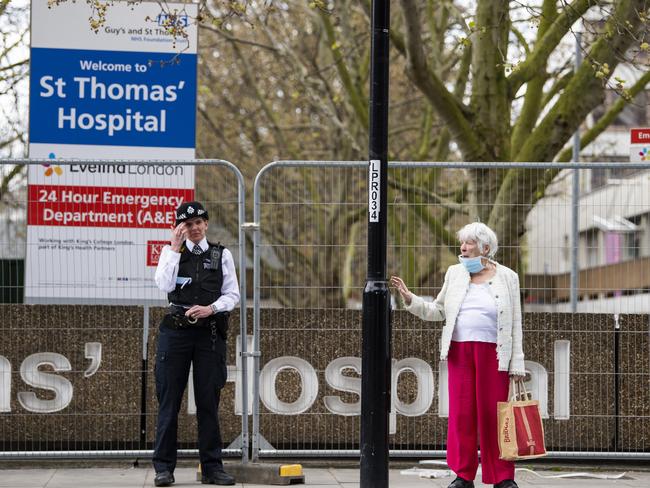 Police stand guard as a woman in a mask looks on outside St Thomas' hospital in London where Boris Johnson is a patient. Picture: Getty Images