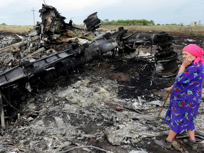 (FILES) A local resident stands among the wreckage at the site of the crash of Malaysia Airlines MH17 aircraft carrying 298 people from Amsterdam to Kuala Lumpur at Grabove, in rebel-held east Ukraine on July 19, 2014. The families of the victims of the downing of flight MH17 in war-torn eastern Ukraine are this week commemorating ten years since the tragedy, with dwindling hopes of seeing those responsible behind bars. (Photo by Alexander KHUDOTEPLY / AFP)