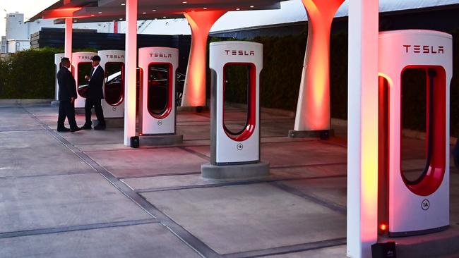 People stand beside charging stations before entry to see the unveiling of the new Tesla Model Y at the Tesla Design Center in Hawthorne, California, on March 14, 2019. - Tesla introduced a new electric sports utility vehicle slightly bigger and more expensive than its Model 3, pitched as an electric car for the masses. Tesla chief executive Elon Musk showed off the "Model Y" late Thursday, March 14, 2019, at the company's design studio in the southern California city of Hawthorne, and the company began taking orders online. (Photo by Frederic J. BROWN / AFP)