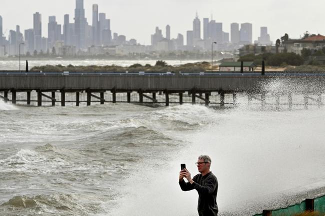 A man photographs the waves in Port Phillip Bay in Melbourne as tens of thousands of people were left without power due to wild storms battering Australia