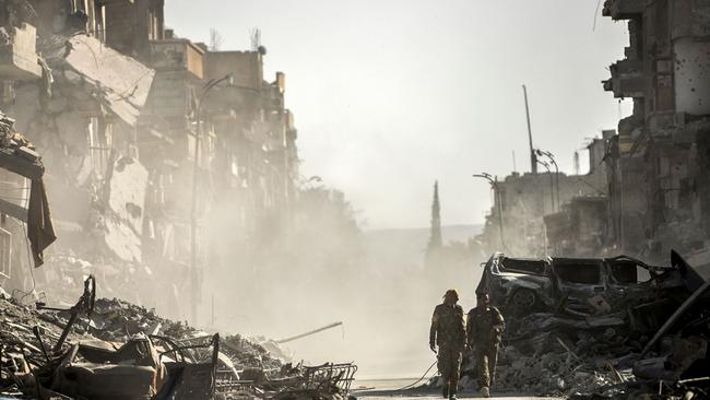 Fighters of the Syrian Democratic Forces (SDF) walk down a street in Raqqa in October after IS fighters were expelled from the city. Picture: Bulent Kilic/AFP