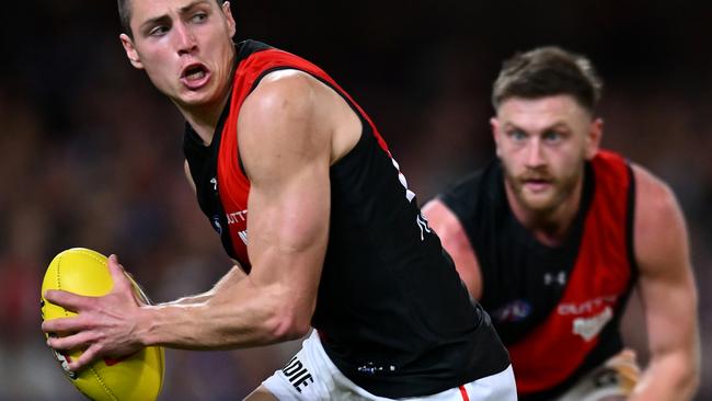 BRISBANE, AUSTRALIA - AUGUST 24: Jake Kelly of the Bombers handles the ball during the round 24 AFL match between Brisbane Lions and Essendon Bombers at The Gabba, on August 24, 2024, in Brisbane, Australia. (Photo by Albert Perez/Getty Images)