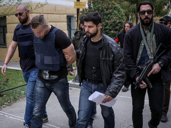 A 31-year-old Bulgarian man is led away by armed police officers in Greece accused of the murder of Australian John Macris in Athens. Picture: Eurokinissi 