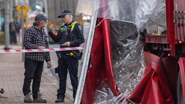 Police speak to a man at the scene of the crash, where a truck lost its load of bottles on South Road, near the intersection of Sir Donald Bradman Drive. Picture: Mark Brake