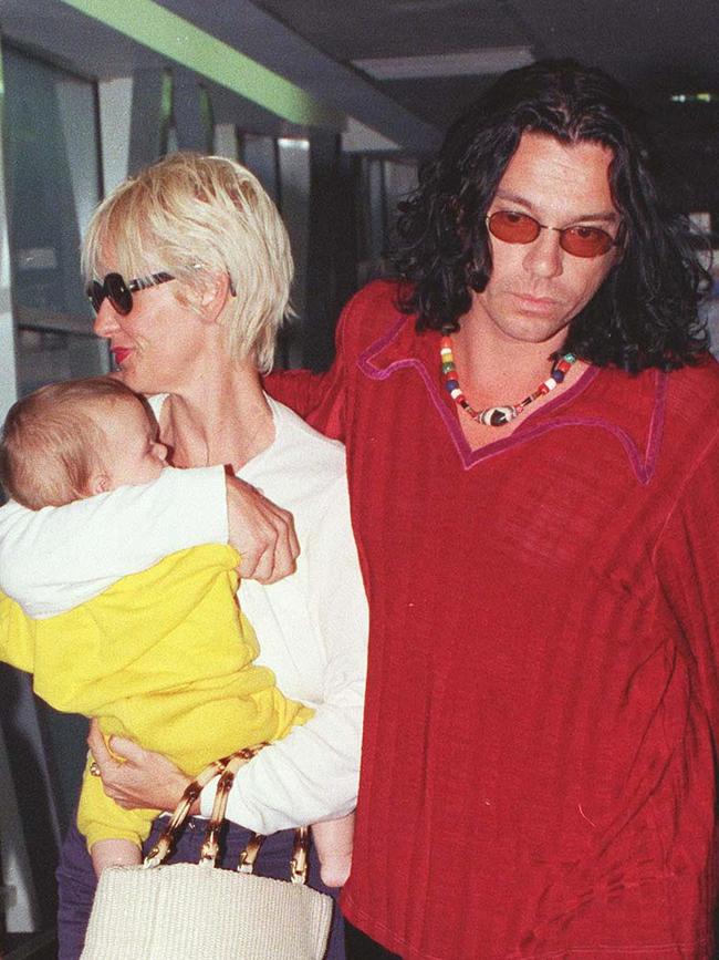 Yates holds Tiger Lily as she and Hutchence walk through Heathrow Airport in London. File picture