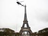 TOPSHOT - This photograph taken in Paris on March 15, 2022 shows a new antenna installed by a Eurocopter AS355N Ecureuil 2 at the top of the Eiffel Tower. (Photo by Christophe ARCHAMBAULT / AFP)