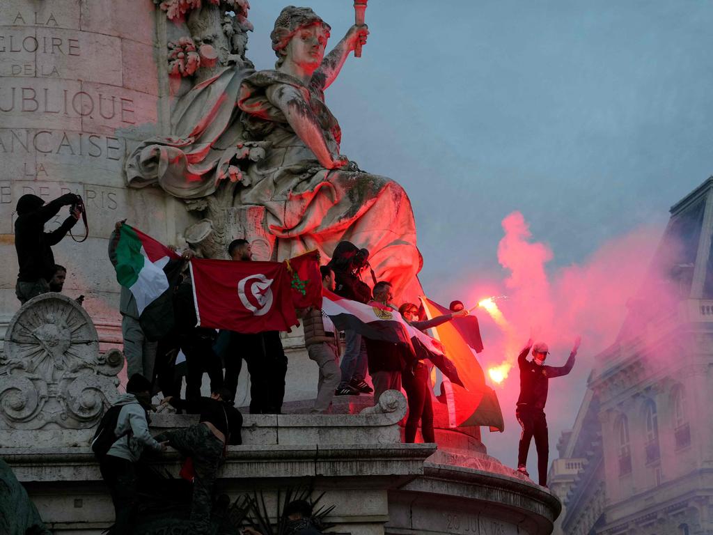 Protesters light flares as they climb on the Monument a la Republique during a demonstration in support of Palestinians in Paris. Picture: AFP