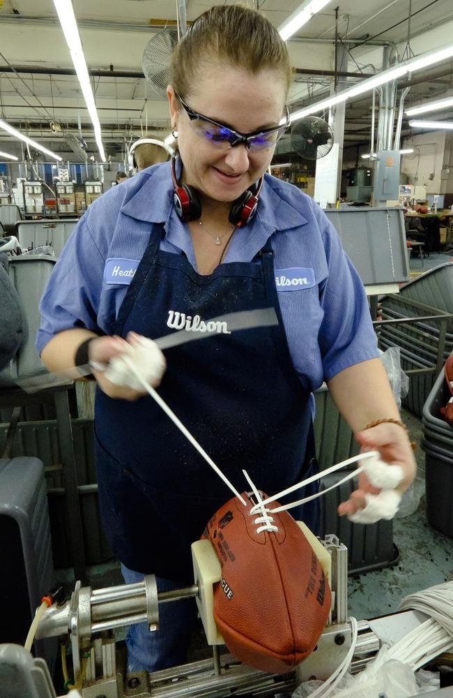 A factory worker from Wilson ties laces on the ball.
