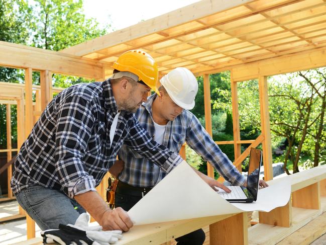 Developing Queensland  - Construction workers on a background of a frame house.