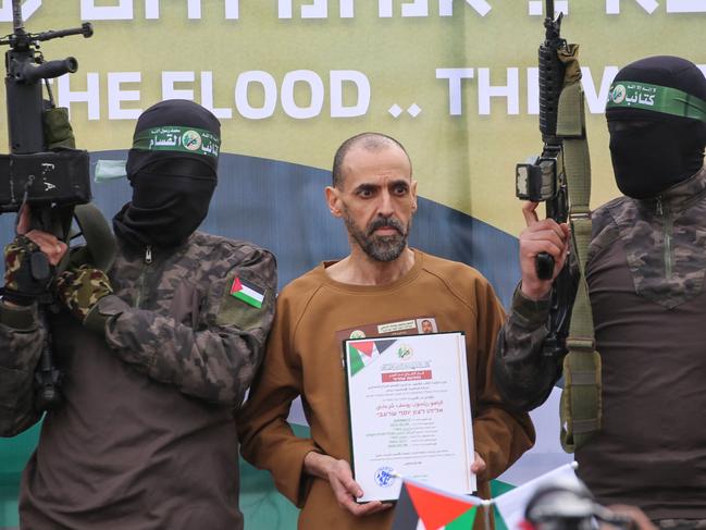 CORRECTION / Hamas fighters escort Israeli hostage Eli Sharabi on a stage before handing him over to a Red Cross team in Deir el-Balah, central Gaza, on February 8, 2025. Hamas militants handed over three Israeli hostages on February 8, as part of the fifth exchange under a fragile Gaza ceasefire, with 183 prisoners held by Israel due to be released later in the day. (Photo by Eyad BABA / AFP) / âThe erroneous mention[s] appearing in the metadata of this photo by Eyad BABA has been modified in AFP systems in the following manner: [Eli Sharabi] instead of [Or Levy]. Please immediately remove the erroneous mention[s] from all your online services and delete it (them) from your servers. If you have been authorized by AFP to distribute it (them) to third parties, please ensure that the same actions are carried out by them. Failure to promptly comply with these instructions will entail liability on your part for any continued or post notification usage. Therefore we thank you very much for all your attention and prompt action. We are sorry for the inconvenience this notification may cause and remain at your disposal for any further information you may require.â