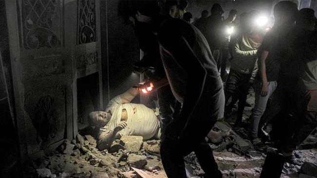 Rescuers approach an injured Palestinian lying in the rubble of a building hit by Israeli bombardment in Rafah on May 7. Picture: AFP