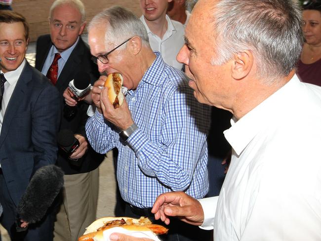 Hungry for a win ... The PM and John Alexander enjoy a ‘democracy sausage’ today.