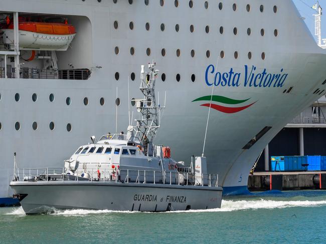 A law enforcement agency sails past the Costa Victoria after it docked at Civitavecchia, 70km northwest of Rome on March 25. Picture: AFP