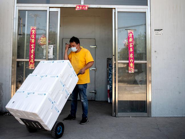 A worker speaks on a mobile phone while transporting boxes at the closed Xinfadi Market in Beijing. Picture: AFP