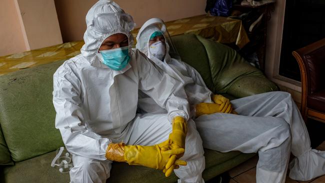 Members of a squad of public safety officers, specialising in preparing those suspected of dying of Covid-19 for burial, rest after helping a family prepare the body of a relative for burial on July 13. Picture: Getty Images