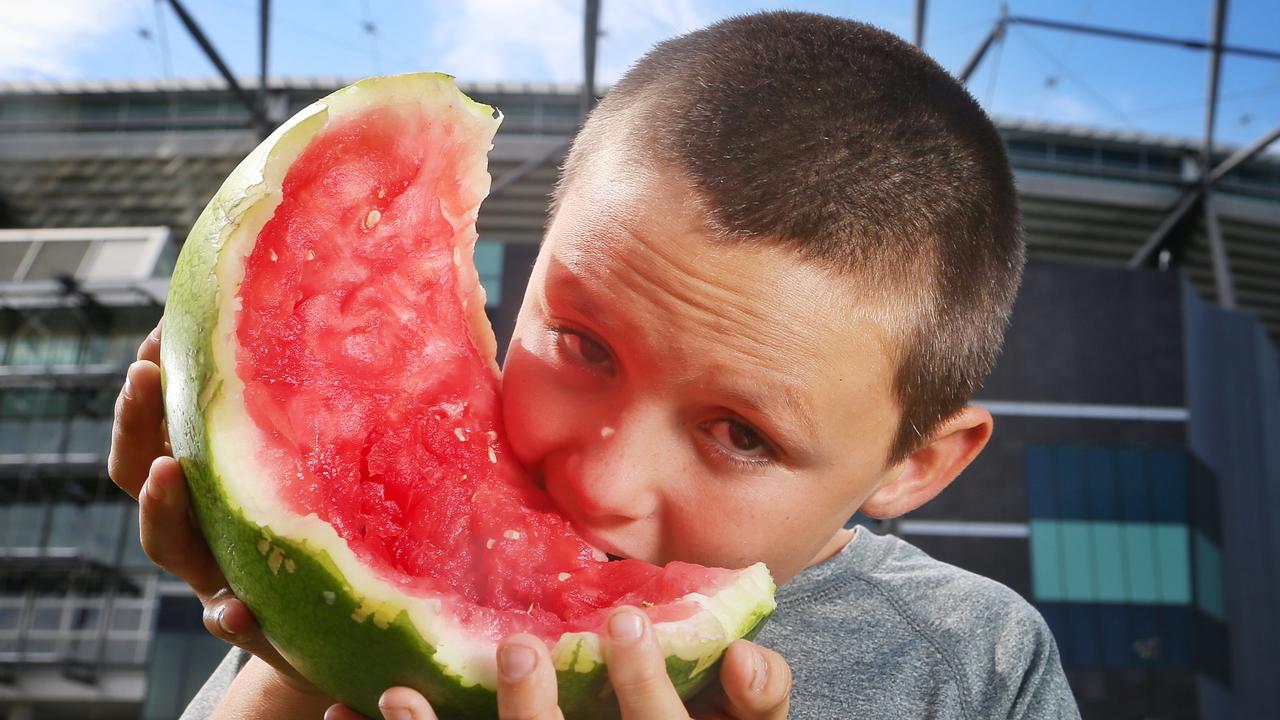 Mitchell Schibeci, better known as “Watermelon Boy”, chows down outside the MCG. Picture: Hamish Blair