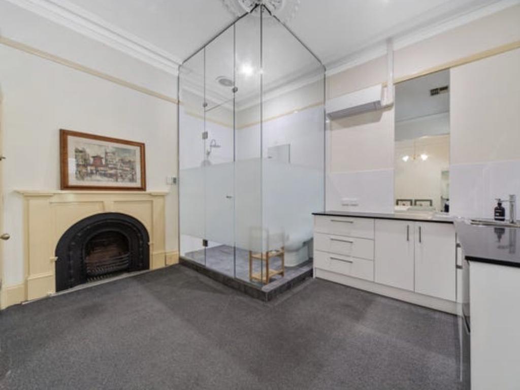 A boxy North Adelaide apartment featuring its own glass shower smack bang in the middle of the kitchen has listed for $400