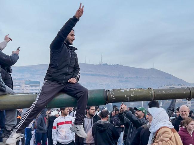 People sitting on a tank as they gather at Umayyad Square in Damascus on December 8, 2024. Islamist-led rebels declared that they have taken Damascus in a lightning offensive. Picture: AFP