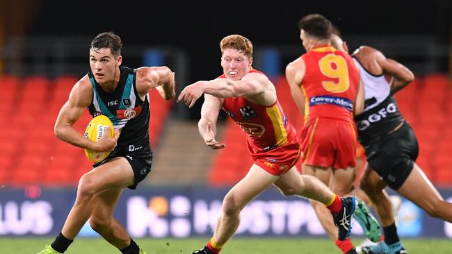 Connor Rozee (left) of the Power gets past Matthew Rowell (centre) of the Suns during the Round 1 AFL match between the Gold Coast Suns and Port Adelaide Power at Metricon Stadium on the Gold Coast, Saturday, March 21, 2020. (AAP Image/Darren England) NO ARCHIVING, EDITORIAL USE ONLY