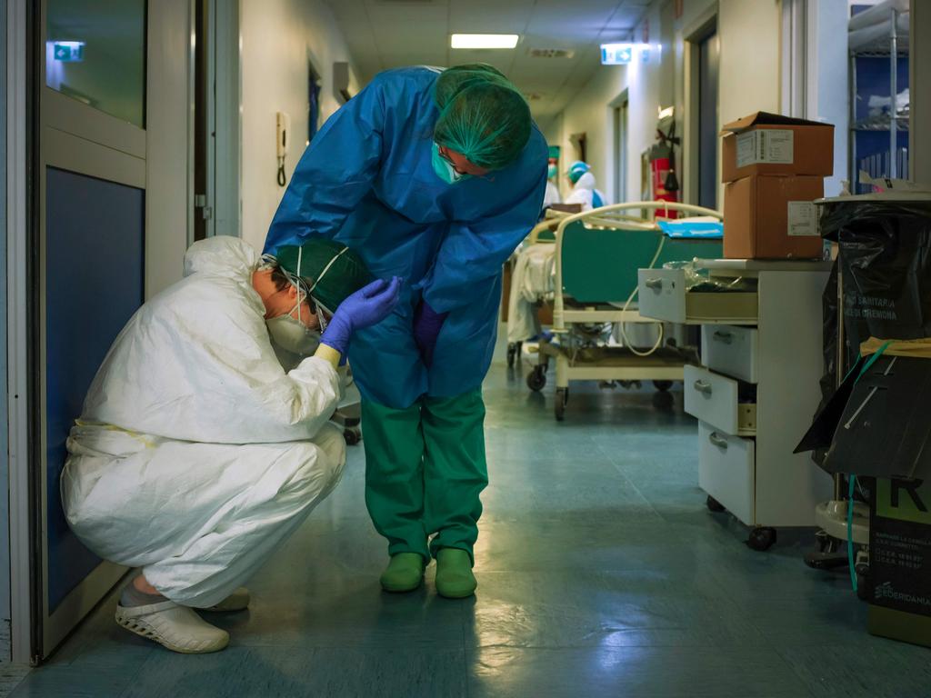 A nurse wearing protective mask and gear comforts another as they change shifts on March 13, 2020 at the Cremona hospital, southeast of Milan in Italy. Picture: Paolo MIRANDA / AFP