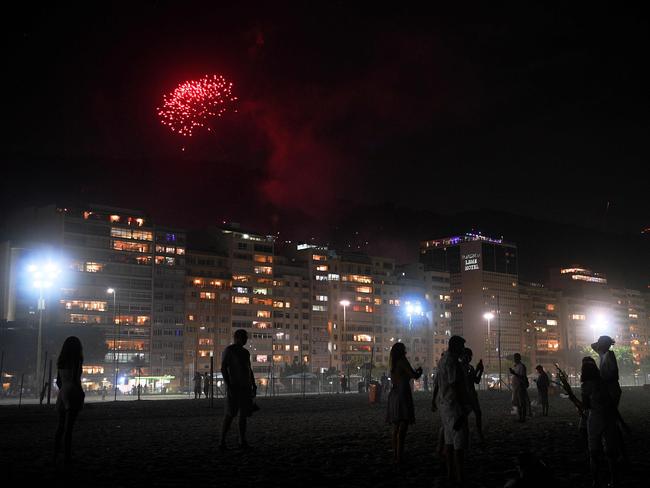 Revellers watch fireworks launched from a nearby favela on an almost empty Copacabana beach on New Years Eve, Rio de Janeiro, Brazil. Picture: AFP