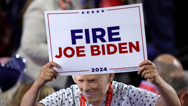 An attendee wearing a US President Joe Biden mask holds a sign calling for him to be fired at the Republican National Convention.