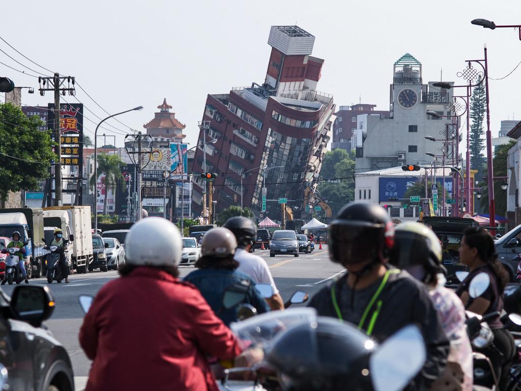 Local residents ride past a building damaged by an earthquake in Hualien on April 4, 2024.. At least nine people were killed and more than 1000 injured by a powerful earthquake in Taiwan that damaged dozens of buildings and prompted tsunami warnings as far as Japan and the Philippines. Picture: AFP