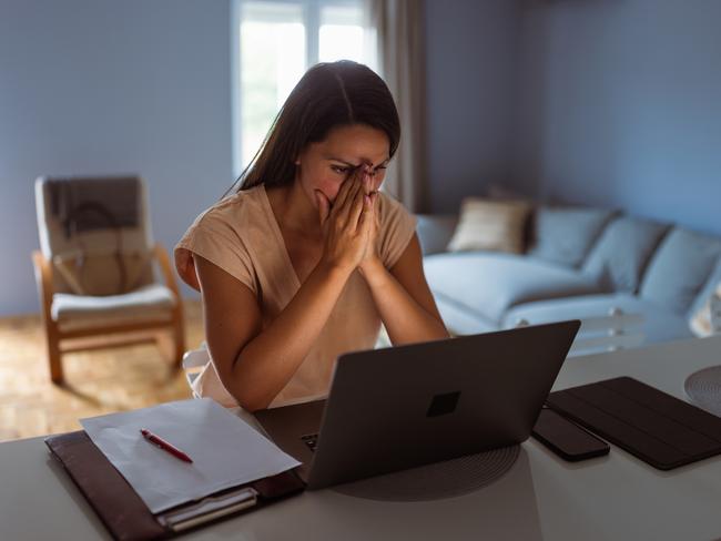 Female victim of financial fraud, looking anxious. She is at her home, discovering financial fraud; scams, scammer generic