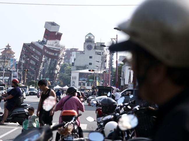 TOPSHOT - Residents ride past a building damaged by the earthquake in Hualien on April 4, 2024. At least nine people were killed and more than 1,000 injured by a powerful earthquake in Taiwan that damaged dozens of buildings and prompted tsunami warnings as far as Japan and the Philippines before being lifted. (Photo by Sam Yeh / AFP)