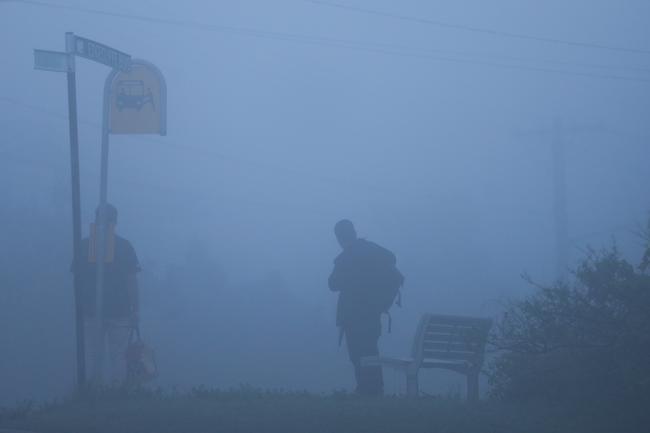 The day after a east coast low battered Sydney and the northern beaches, people wait for a bus at Collaroy. Picture: John Grainger