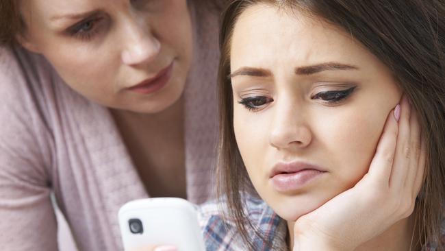 Mother Comforting Daughter Being Bullied By Text Message - Stock Image