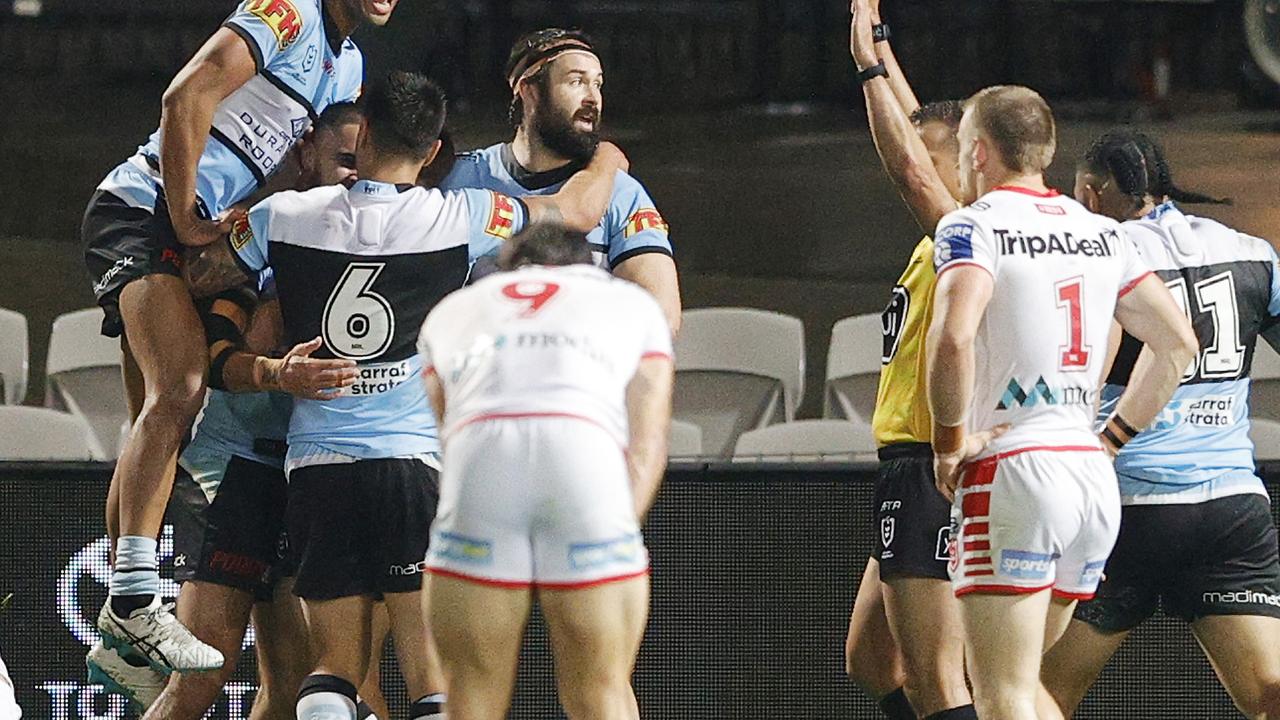 Sharks players celebrate a try against the Dragons.