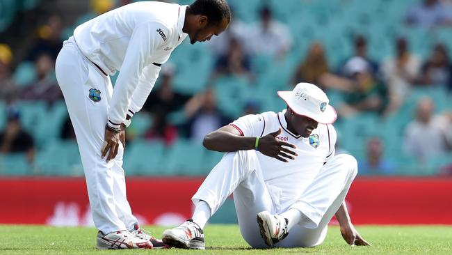 Windies captain Jason Holder (R) checks his injured hand as vice-captain Kraigg Brathwaite (L) looks on during the final day of the third cricket Test match played in Sydney on January 7, 2016. AFP PHOTO / William WEST --IMAGE RESTRICTED TO EDITORIAL USE - NO COMMERCIAL USE--