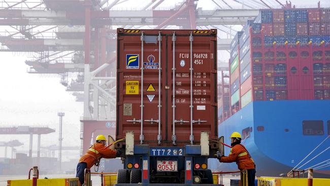 In this Jan. 14, 2019, photo, workers check on a container before loading to a cargo ship at the Qingdao port in east China's Shandong province. China's economic growth fell to a three-decade low in 2018 as business activity lagged amid a tariff war with Washington. (Chinatopix via AP)