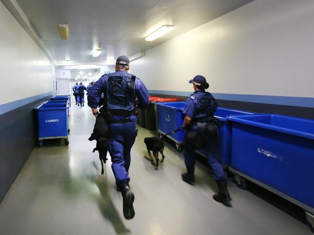 Corrective Services officers run as quietly as possible to a cell block to execute a raid on cells at Silverwater Jail looking for contraband. The officers now wear body cams that record the raids. Picture: Richard Dobson